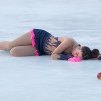 mladá krasokorčuliarka leží na ľadovej ploche